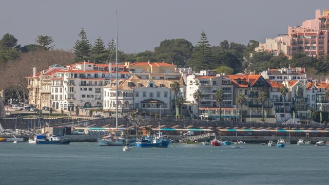 Boats and yachts floating on the water of Cascais bay with Palacete Seixas. Timelapse showcasing the scenic waterfront, historic architecture and coastal charm with houses and cranes in the background