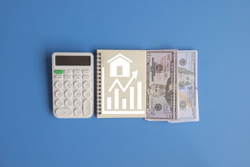 A calculator, cash, and a notebook with an upward growth graph, visualizing the process of real estate investment, financial analysis, and the increasing value of the housing market.
