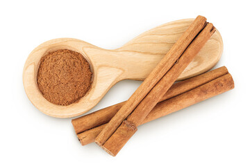 Cinnamon sticks with powder in wooden spoon isolated on white background. Top view. Flat lay.
