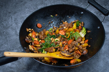 Stir fry made with seitan and various veggies, mushrooms in black cast iron wok