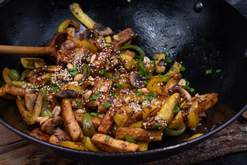 Vegan tofu, mushroom, pepper and squash stir fry in wok