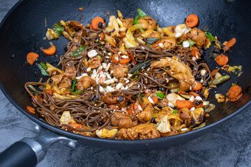 Yuba knots and veggie stir fry in cast iron wok, plant based Asian healthy food