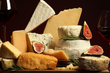 Different types of cheese, rosemary, figs and wine on table, closeup