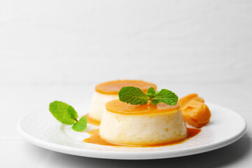 Tasty puddings with caramel sauce served on white tiled table, closeup. Space for text