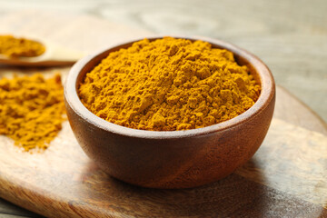 Turmeric powder in bowl on table, closeup