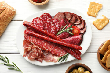 Different smoked sausages slices served on white wooden table, flat lay