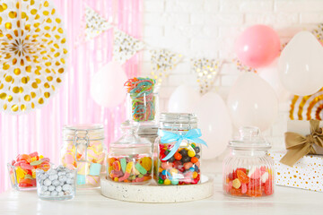 Candy bar. Many different sweets on white wooden table in festive decorated room