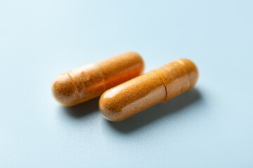 Turmeric capsules on light blue background, closeup