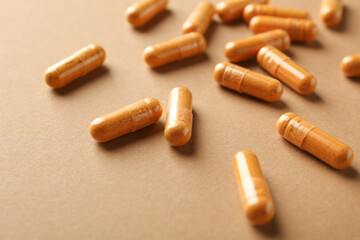 Many turmeric capsules on beige background, closeup