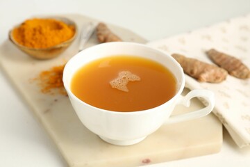 Aromatic turmeric tea, powder and rhizomes on white table, closeup