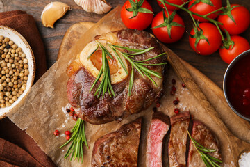 Pieces of delicious beef meat, spices and tomatoes on wooden table, flat lay
