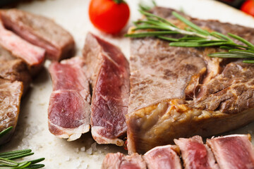 Pieces of delicious beef meat, spices and tomato on plate, closeup