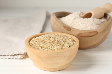 Brown rice and flour on white wooden table, closeup
