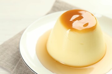 Delicious pudding with caramel sauce on table, closeup. Space for text
