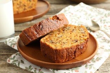 Pieces of homemade carrot cake with nuts and spoon on wooden table, closeup