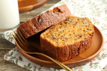 Pieces of homemade carrot cake with nuts and fork on wooden table, closeup