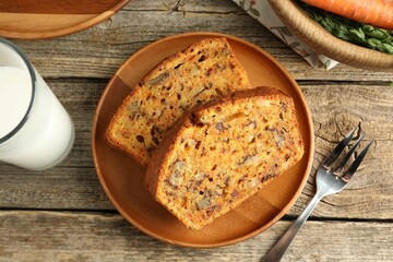 Homemade carrot cake with nuts, milk and fork on wooden table, flat lay