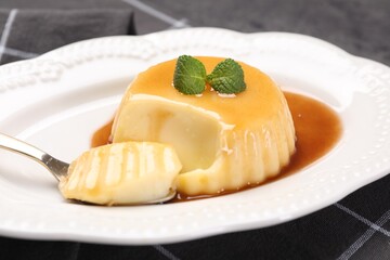 Delicious pudding with caramel sauce and mint served on table, closeup