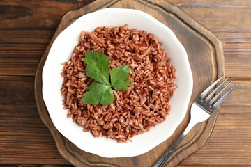 Delicious brown rice with parsley served on wooden table, top view