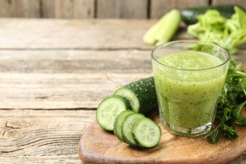 Healthy parsley smoothie in glass, leaves and cucumber on wooden table, closeup. Space for text