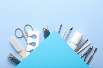 Set of different manicure tools on light blue background, flat lay. Space for text