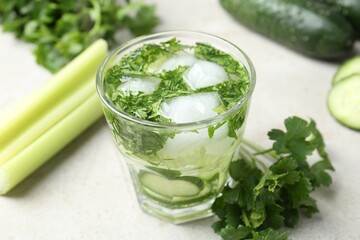Healthy drink with parsley, cucumbers and celery on light table, closeup