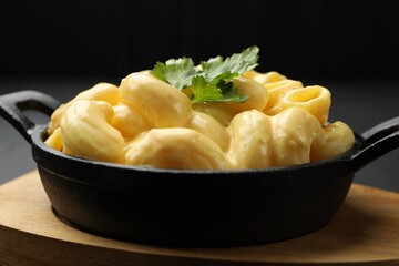Delicious macaroni and cheese on black table, closeup