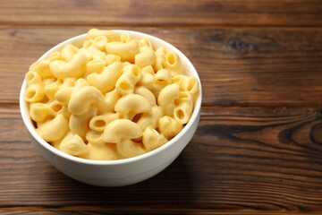 Delicious macaroni and cheese on wooden table, closeup. Space for text