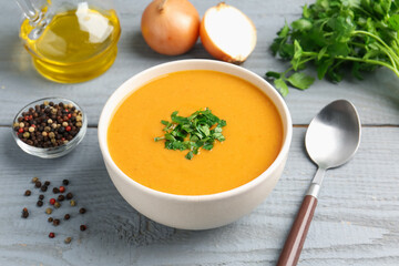 Delicious lentil cream soup with parsley served on grey wooden table, closeup