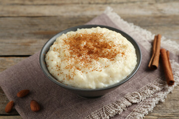 Delicious rice pudding with cinnamon and almonds on wooden table, closeup