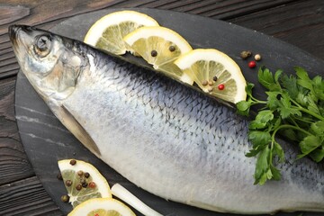 Salted herring and spices on wooden table, top view