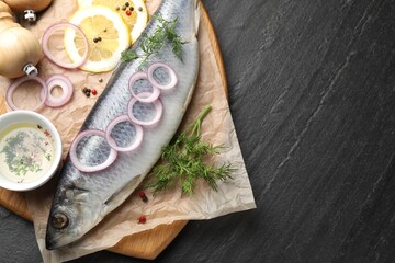 Tasty herring with spices on black table, flat lay. Space for text