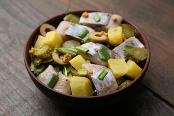 Delicious salad with herring on wooden table, closeup