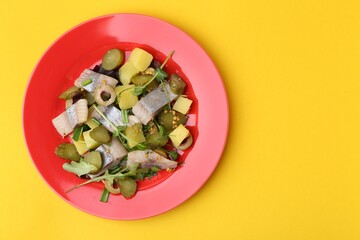 Delicious salad with herring on yellow background, top view. Space for text