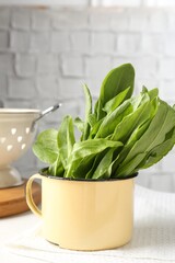 Fresh sorrel leaves in bowl and colander on table