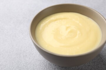 Tasty vanilla pudding in bowl on light grey table, closeup. Space for text
