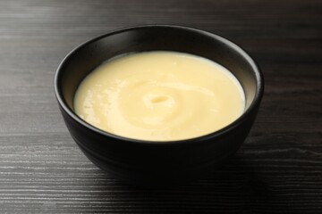 Tasty vanilla pudding in bowl on wooden table, closeup