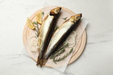 Smoked herrings, onion, rosemary and lemon on white marble table, top view