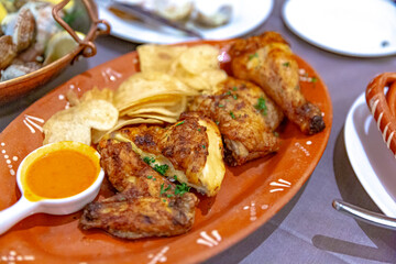 Frango Assado, Portuguese grilled chicken served with chips and spicy sauce on a decorative clay...