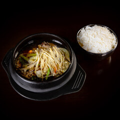 Korean bulgogi stew served with rice, featuring thinly sliced marinated beef, mushrooms, and...