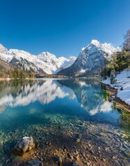 Obraz premium A pristine alpine lake reflecting the snow-capped mountains and clear blue sky