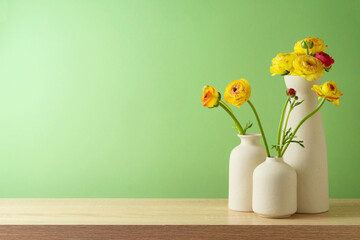 Spring and Easter concept with flowers in modern vase over green wall background. Interior mock up...