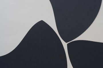three black paper machine-cut forms with curved eges and tapered elements on blank paper