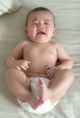 Baby is crying on a bed