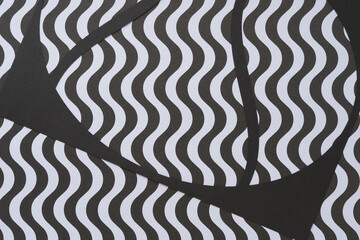 abstract machine-cut black paper stencil on black and white paper with wavy stripes