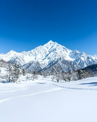 Fototapeta premium Snow-covered mountain landscape under a vibrant blue sky Footprints trail through pristine snow towards majestic peak