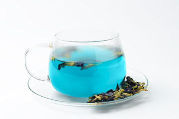 Fresh butterfly pea flower tea in cup and dry petals on white table, closeup
