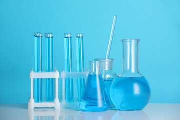 Laboratory glassware with liquid on mirror surface against blue background