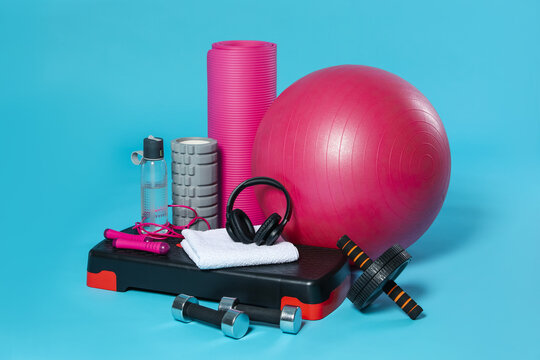 Different fitness equipment and headphones on light blue background