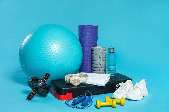 Different fitness equipment and headphones on light blue background